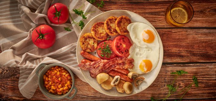 Śniadanie angielskie: pikantna fasolka w pomidorach, wołowe kiełbaski, smażone pieczarki, pomidory, jajka i placuszki Rösti