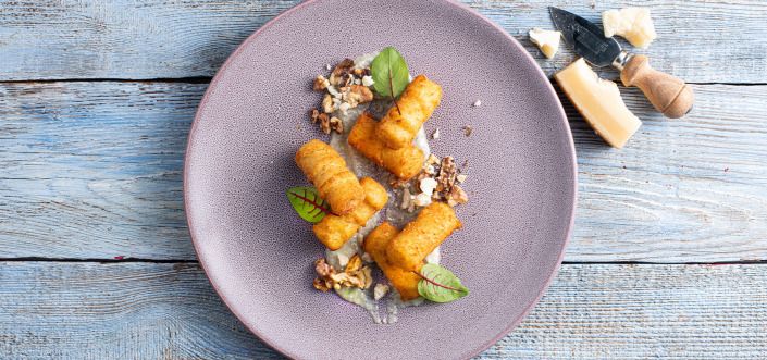 Krokiety ziemniaczane podane z sosem cztery sery i prażonymi orzechami włoskimi